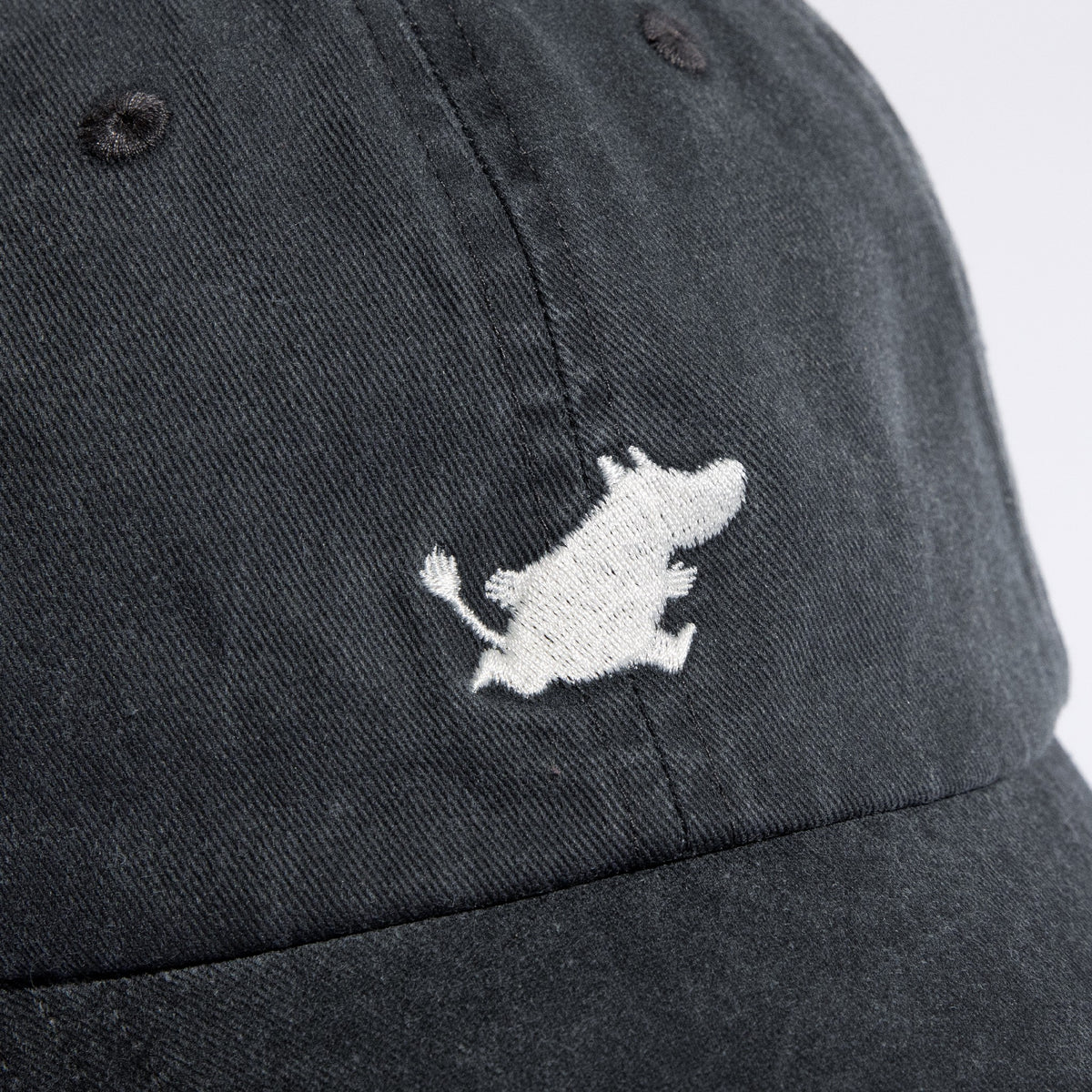 Détail du motif Moomin blanc et de la texture denim gris foncé de la casquette